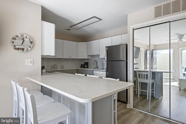 a kitchen with a refrigerator a stove a sink and a dining table with chairs