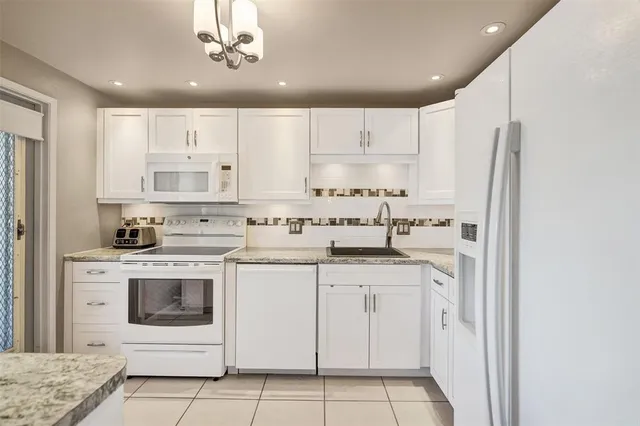 a kitchen with granite countertop white cabinets and white appliances