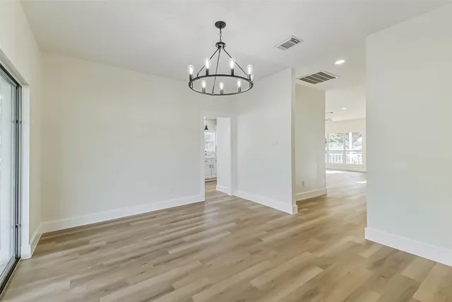 a view of an empty room with wooden floor and fan