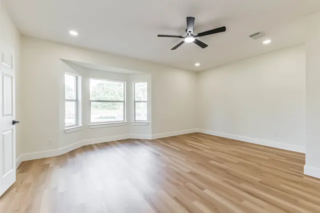 a view of an empty room with a window and wooden floor