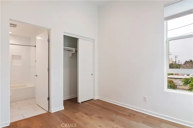 a view of an empty room with window and wooden floor