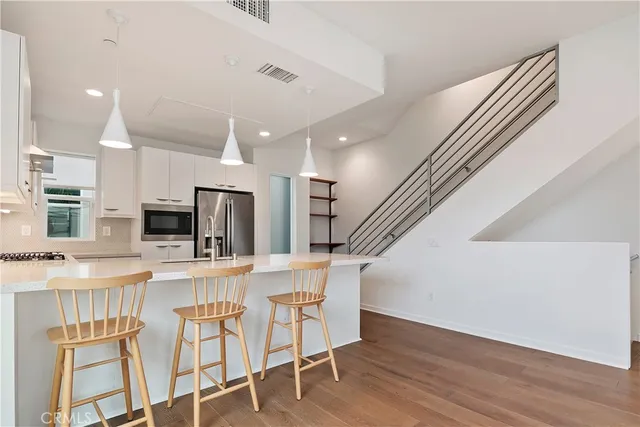 a kitchen with stainless steel appliances kitchen island granite countertop a refrigerator and microwave