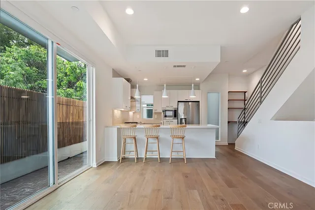 a dining room with stainless steel appliances a large window a table and chairs