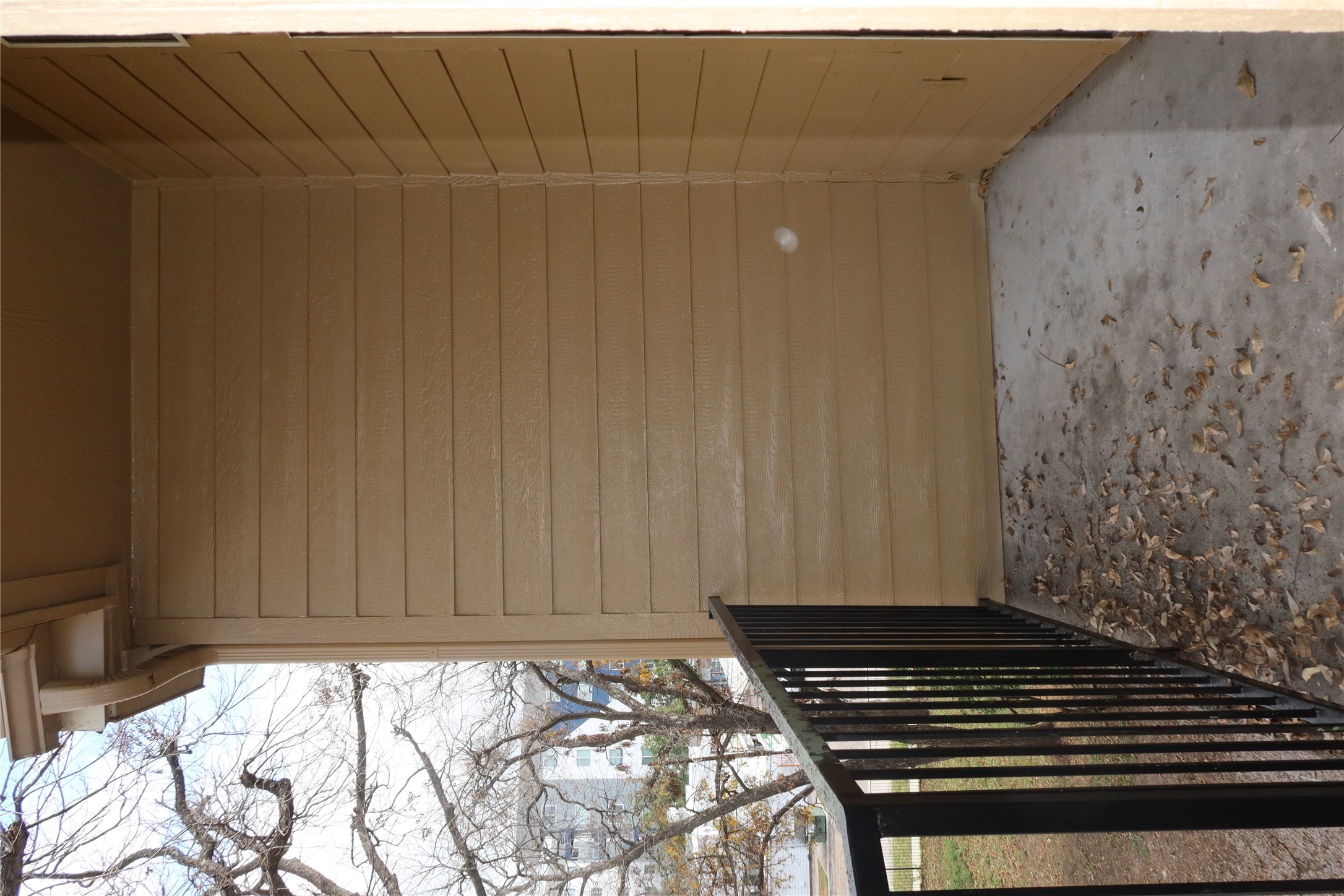 2802 Nueces Street, Unit 306 Austin, TX 78705 - Photo 17 of 20 Balcony with a concrete floor and black metal railing, featuring tan horizontal siding and a soffit ceiling