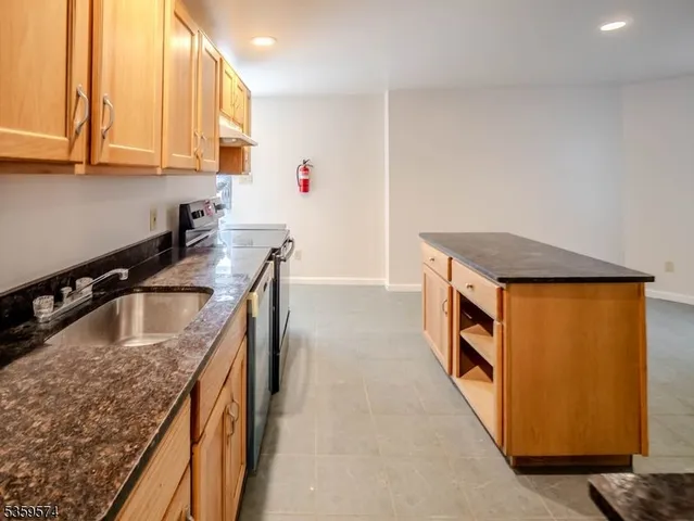 a kitchen with kitchen island granite countertop a sink and a stove
