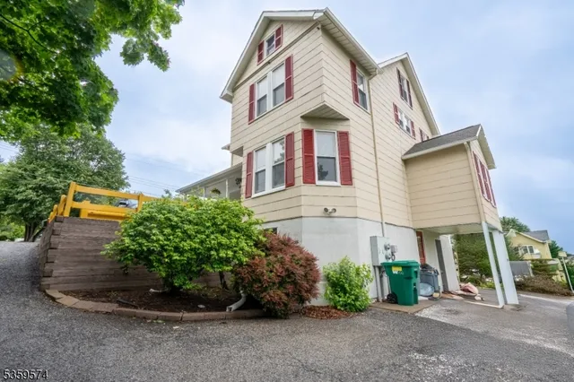 a view of a white house with large windows and a small yard