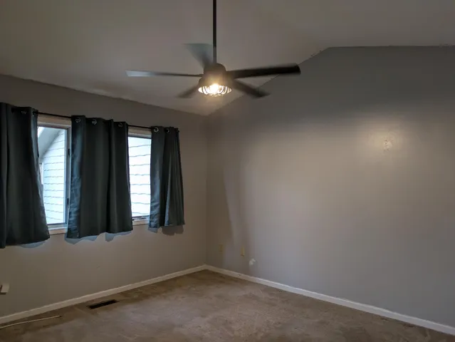 an empty room with windows and fan