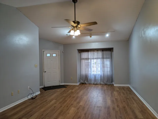 a view of an empty room with window and wooden floor