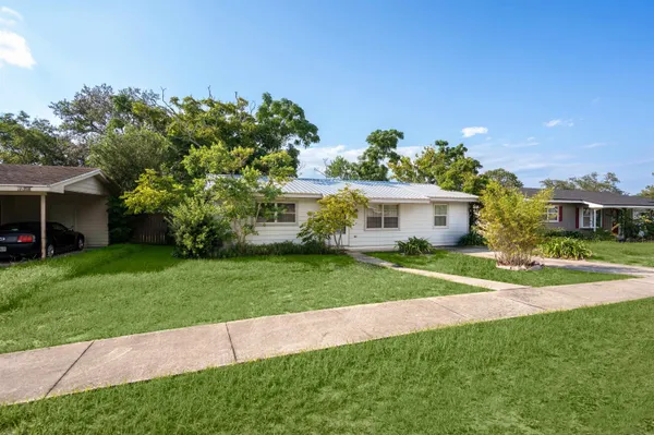 a front view of a house with a yard and trees