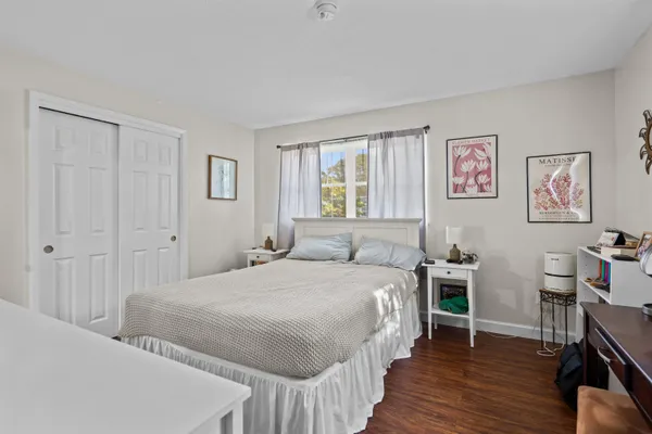 a bedroom with a bed a table and wooden floor
