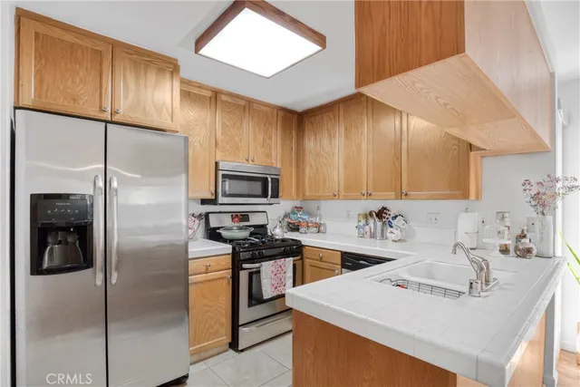 a kitchen with stainless steel appliances a sink a stove a refrigerator cabinets and a refrigerator
