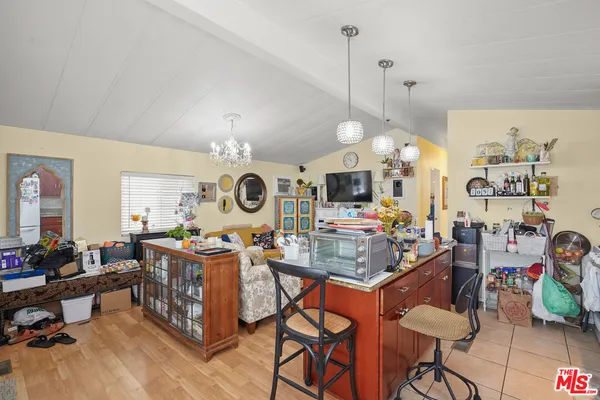 a view of a dining room and livingroom with furniture wooden floor a rug a painting and a chandelier