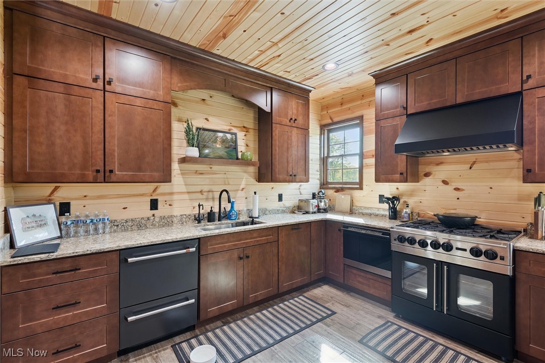 290 Townline Road Aurora, OH 44202 - Photo 15 of 50 Kitchen featuring gas range oven, under cabinet range hood, dishwasher, light wood-style floors, and light stone counters