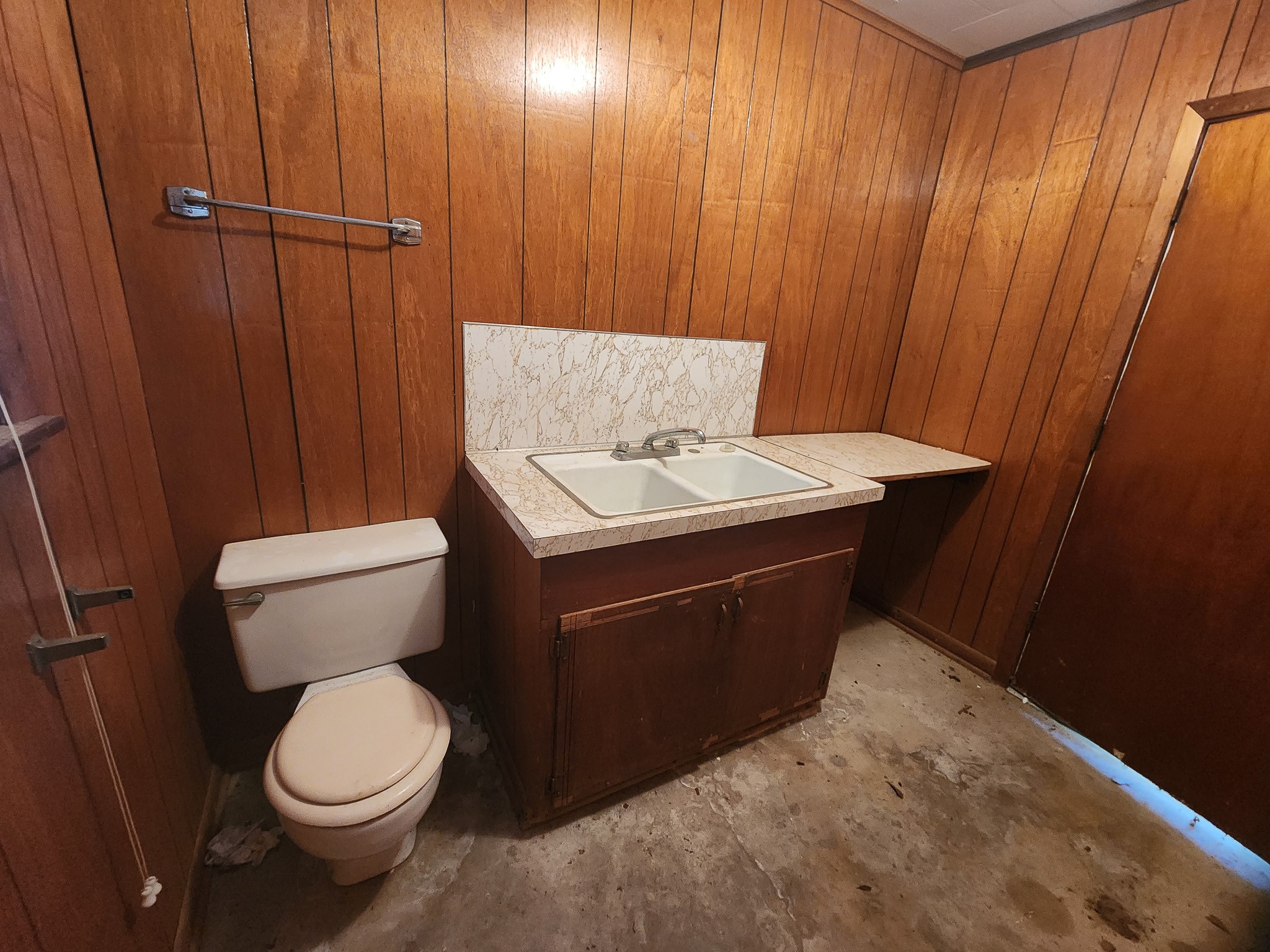 201 Verna Street Jasper, TX 75951 - Photo 17 of 24 Discover potential in this rustic half bath, featuring warm wood paneling and a vintage sink setup, perfect for a creative renovation.