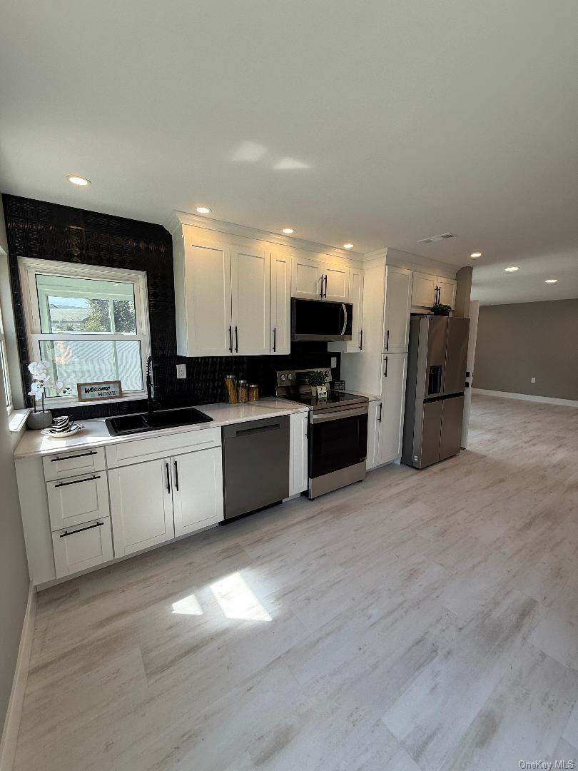 379 Larchmont Court Ridge, NY 11961 - Photo 6 of 17 a large white kitchen with a stove a sink and a refrigerator