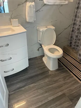 a white toilet sitting next to a sink and vanity