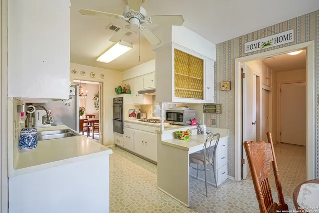 a kitchen with kitchen island a sink a stove a refrigerator cabinets and living room view