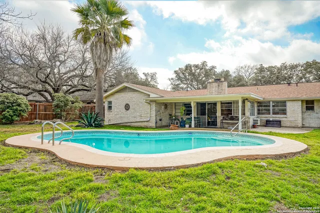 a view of a house with swimming pool and a big yard with large trees