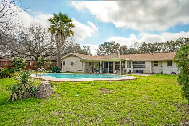 a view of a house with a small yard and large tree