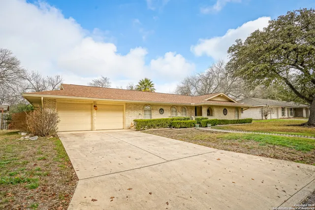 a view of a house with a yard and large trees