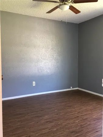 a view of an empty room with a ceiling fan and wooden floor