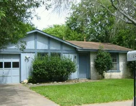 a view of a house with a yard plants and large tree