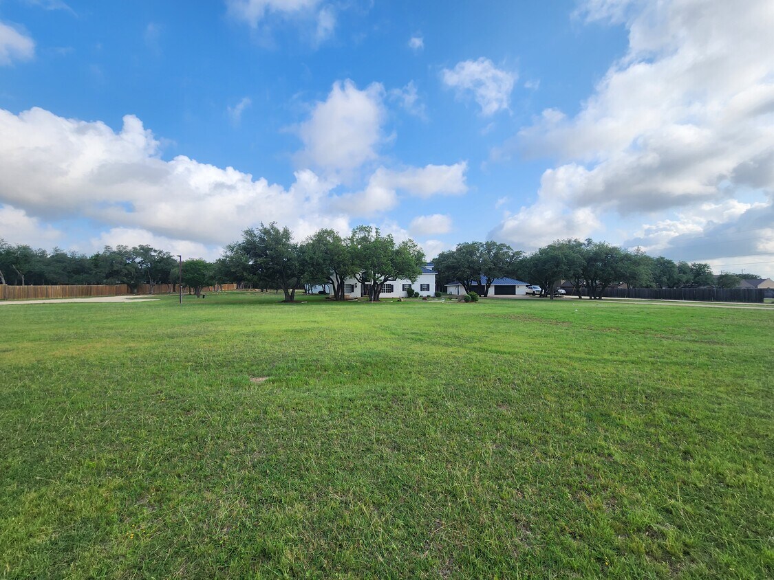 102 County Road 180 Leander, TX 78641 - Photo 14 of 25 A spacious lot provides ample room for outdoor recreation, bordered by a classic wood fence and mature trees.