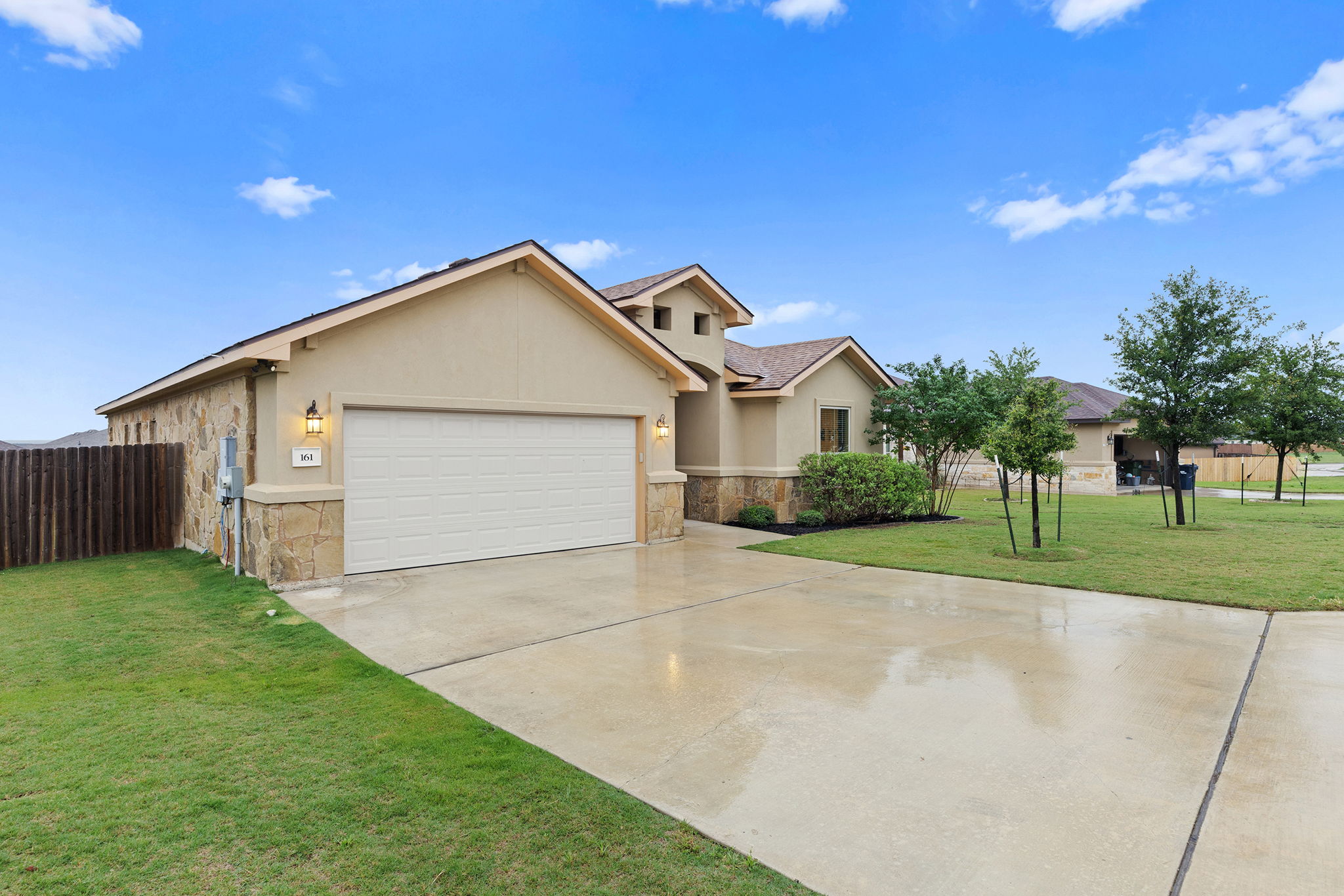 161 Greg Lane Jarrell, TX 76537 - Photo 2 of 35 Stucco and stone exterior with a two-car garage, concrete driveway, and manicured front lawn