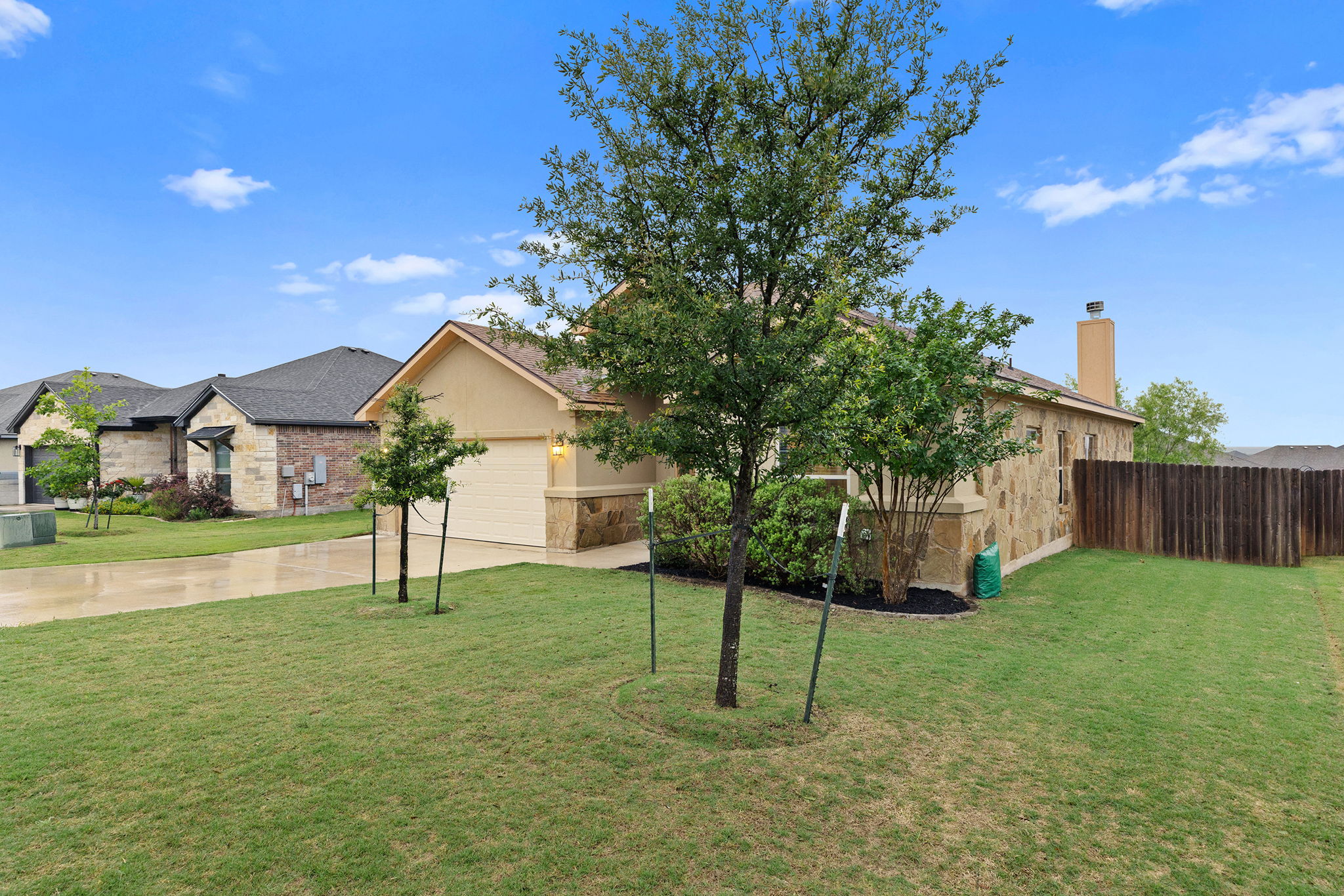161 Greg Lane Jarrell, TX 76537 - Photo 3 of 35 Single-story residence featuring a stone and stucco exterior, an attached garage, a paved driveway, and mature landscaping