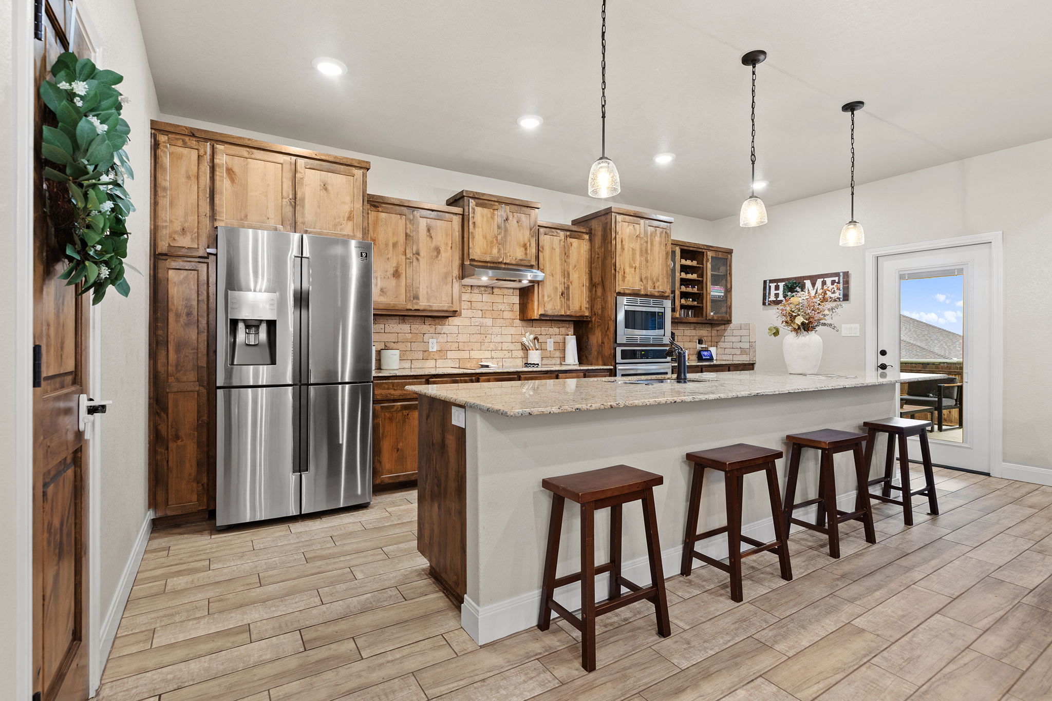 161 Greg Lane Jarrell, TX 76537 - Photo 9 of 35 Spacious kitchen featuring an island with stone countertop, stainless steel appliances, wood-finish flooring, recessed lighting, and pendant fixtures