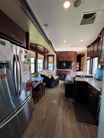 a kitchen with stainless steel appliances granite countertop a refrigerator a sink dishwasher a stove and a dining table with wooden floor