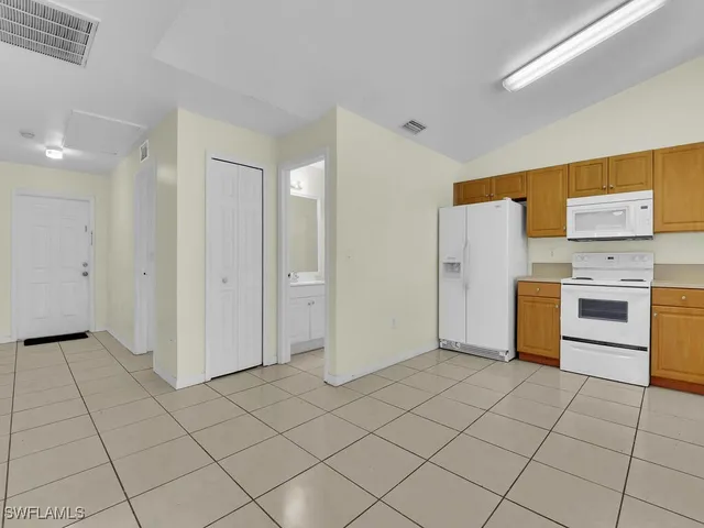 a kitchen with white cabinets a refrigerator and a stove