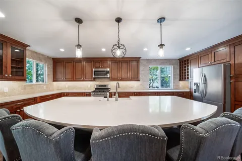 a large kitchen with stainless steel appliances granite countertop a sink a stove and a wooden floors