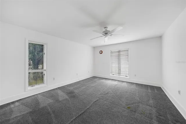 an empty room with a ceiling fan and carpet