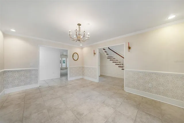 an empty room with a chandelier fan and windows