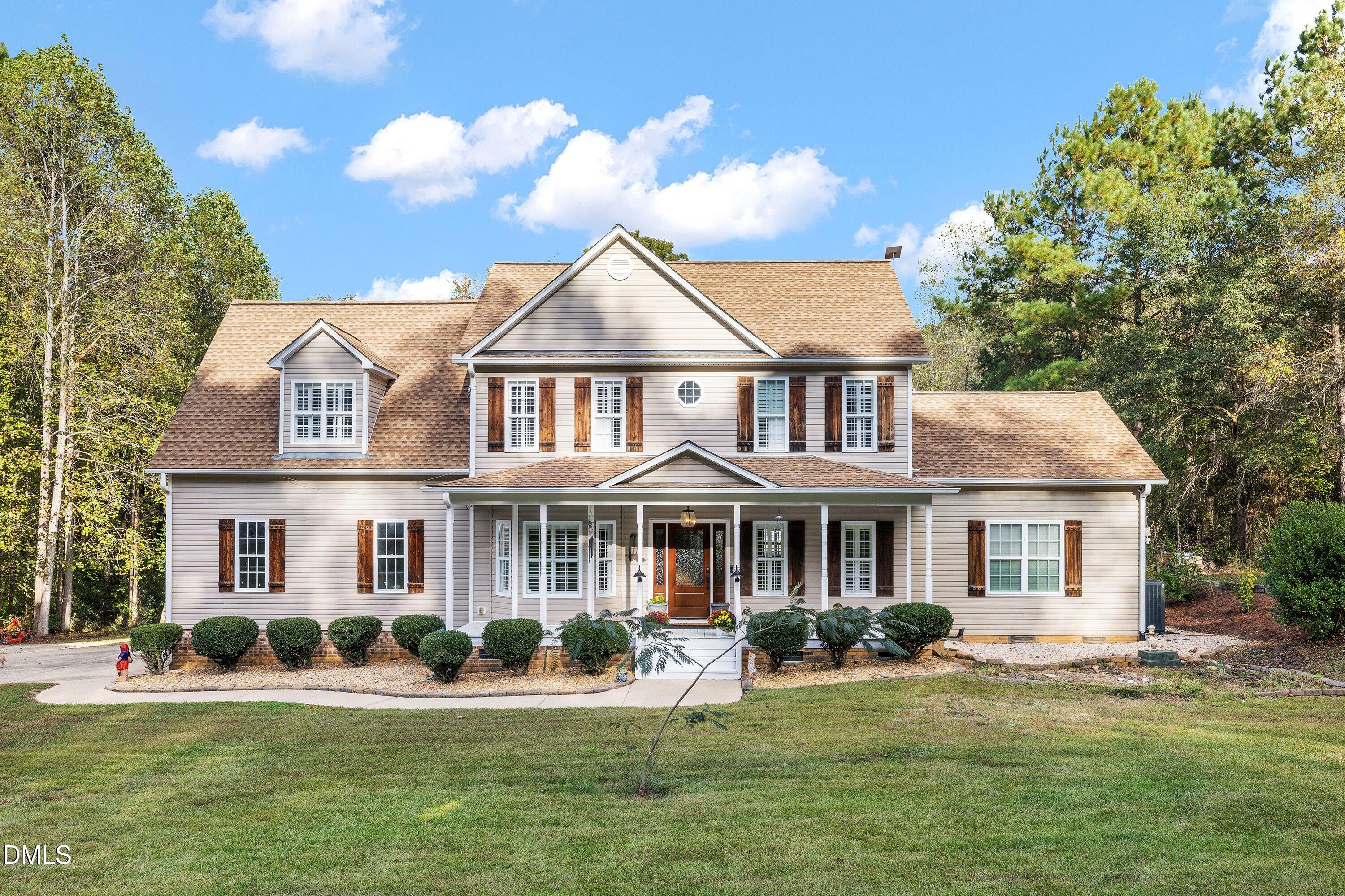 a front view of a house with a garden and trees