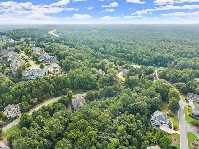 an aerial view of residential houses with outdoor space and trees