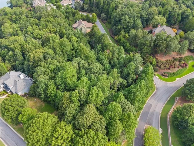 an aerial view of a house with a yard and trees all around
