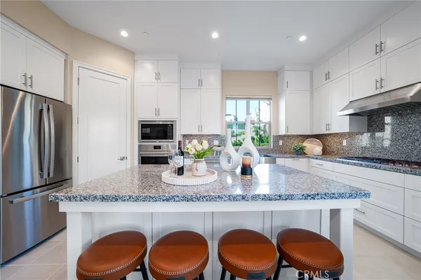 a kitchen with granite countertop stainless steel appliances a sink a stove a refrigerator cabinets and dining table