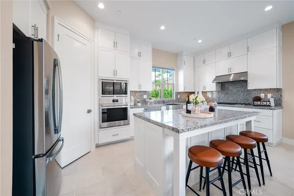a kitchen with stainless steel appliances granite countertop a refrigerator and a stove top oven