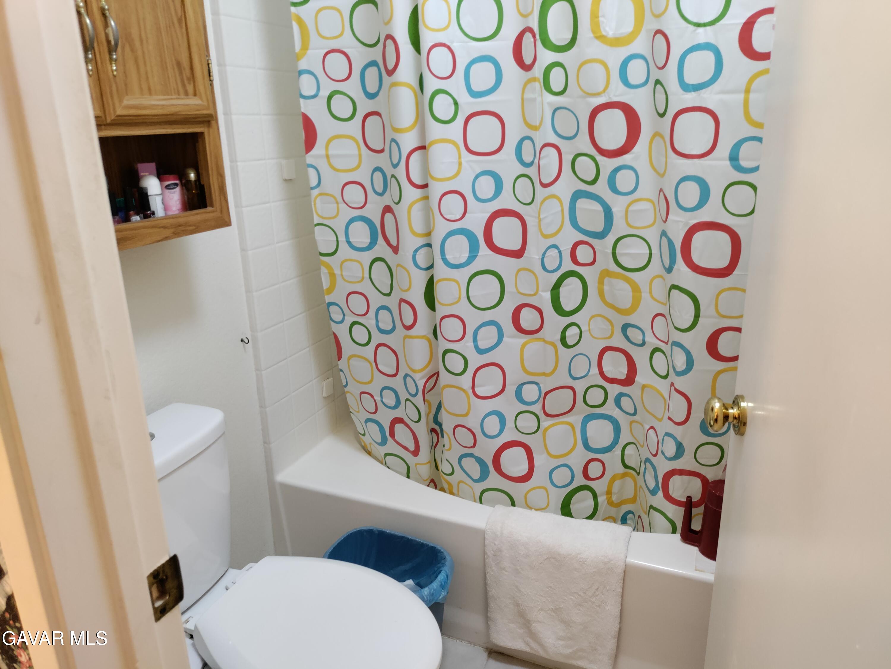 37759 67th Street East Palmdale, CA 93552 - Photo 11 of 27 a white toilet sitting next to a shower curtain