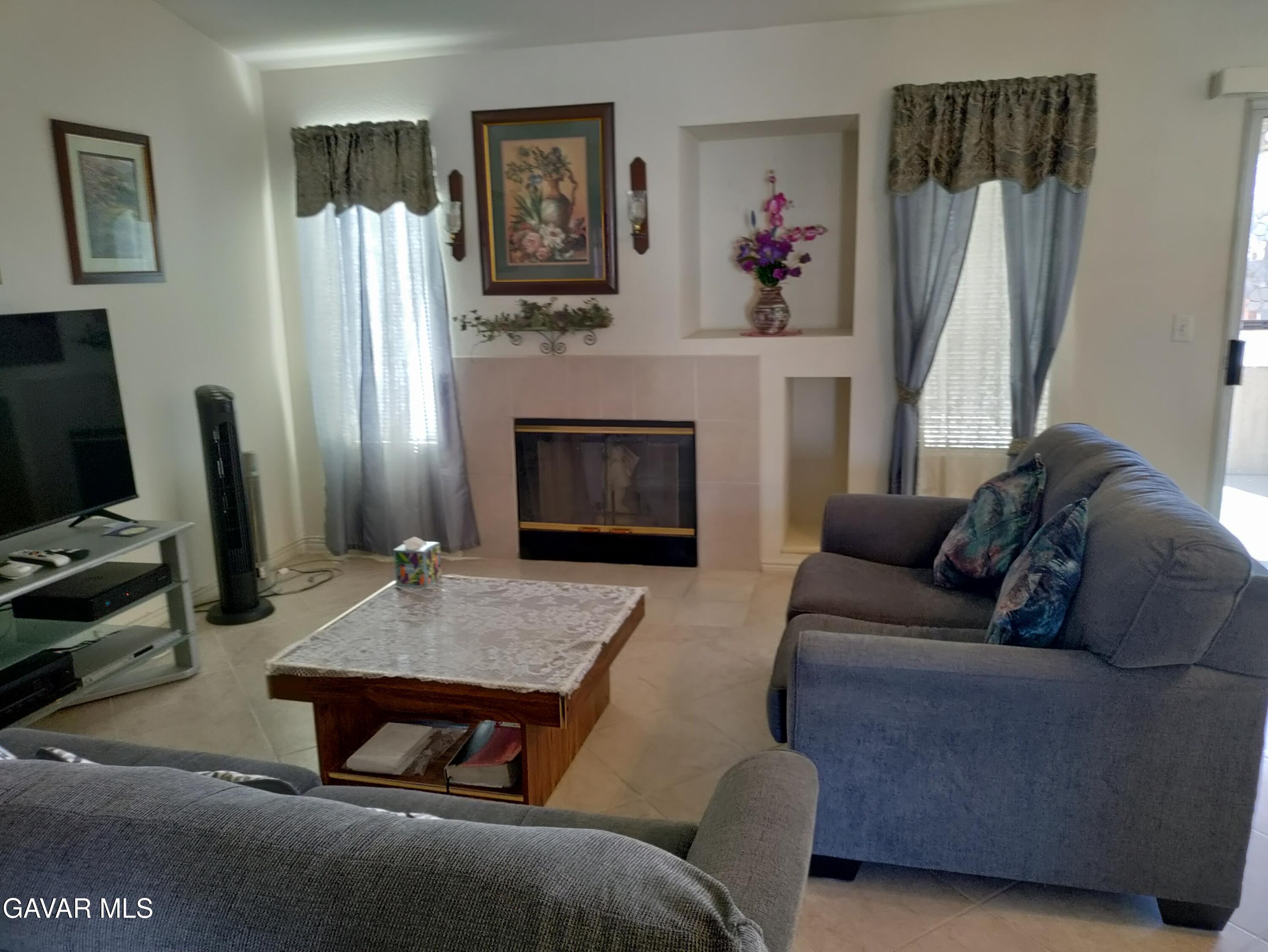 37759 67th Street East Palmdale, CA 93552 - Photo 2 of 27 a living room with furniture a fireplace and a flat screen tv
