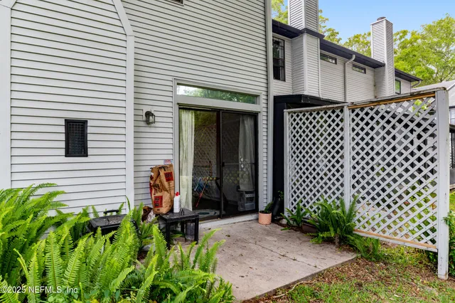 a backyard of a house with plants and large tree