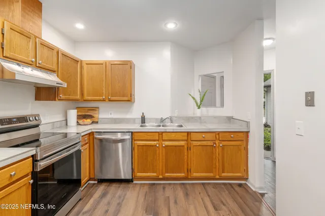 a kitchen with stainless steel appliances kitchen island granite countertop a refrigerator and a sink