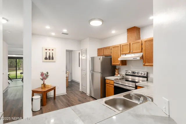 a kitchen with stainless steel appliances granite countertop a sink a stove a refrigerator a microwave oven with wooden floor