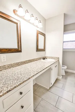 a bathroom with a granite countertop sink a toilet and mirror