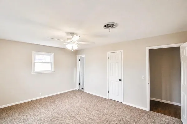 an empty room with a ceiling fan and a window