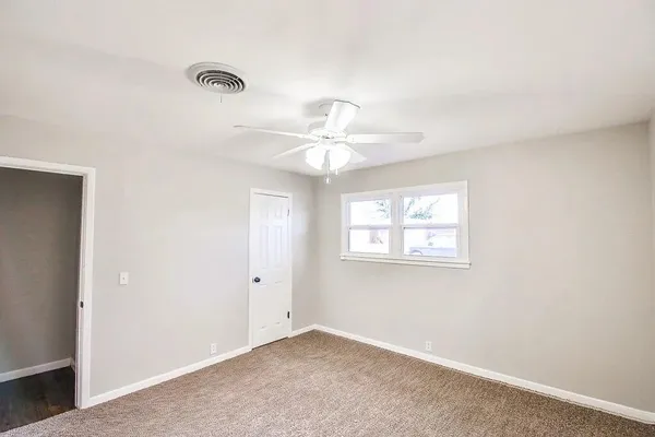 an empty room with windows and fan