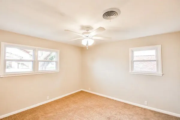 an empty room with windows and fan