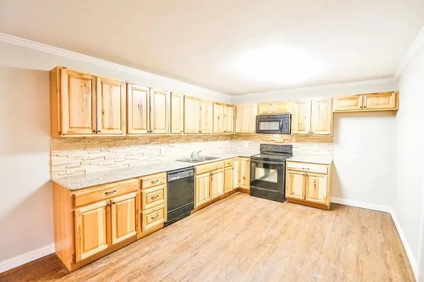 a large kitchen with granite countertop a stove top oven a sink dishwasher and a refrigerator with wooden floor